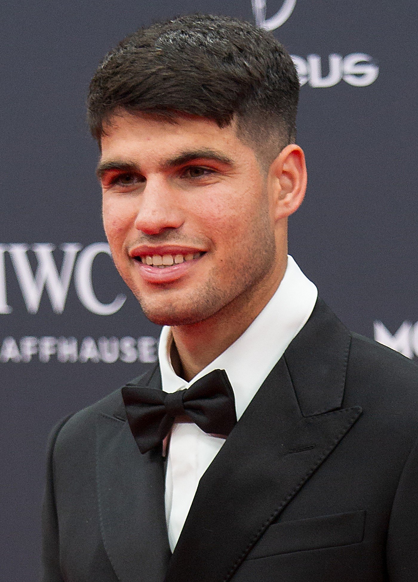 Carlos Alcaraz, portrait souriant en costume sur tapis rouge