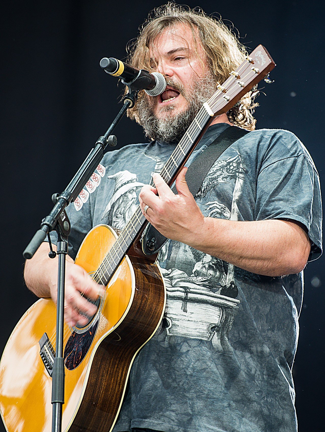Jack Black en concert, guitare acoustique à la main, chantant au micro
