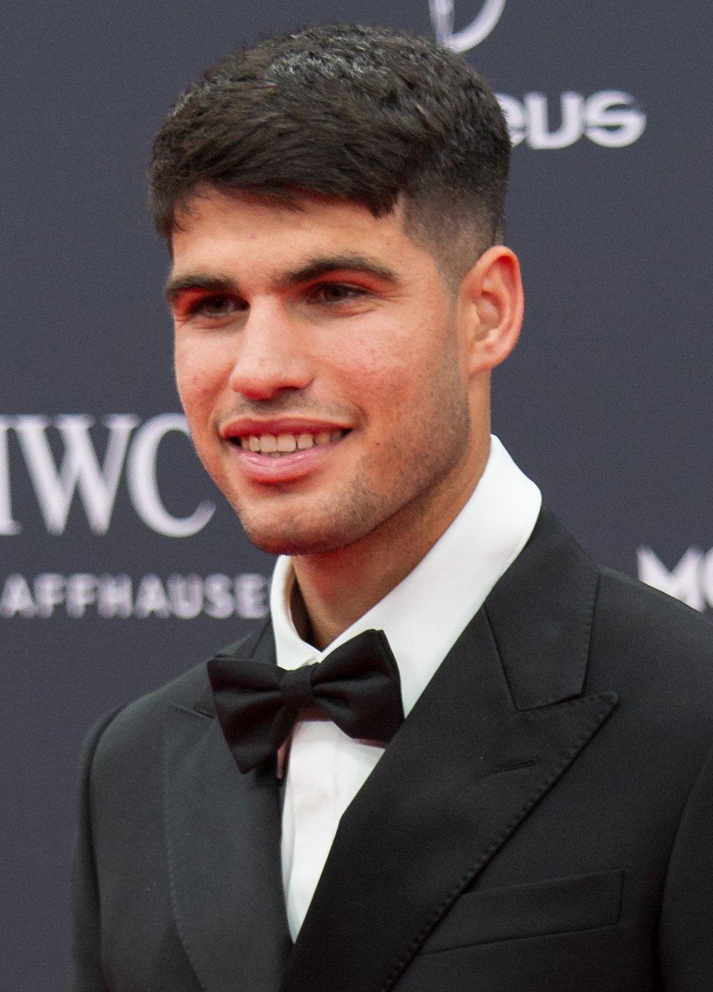 Portrait de Carlos Alcaraz, joueur de tennis espagnol, en costume sur un tapis rouge